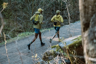 Two persons running on a road through the woods 